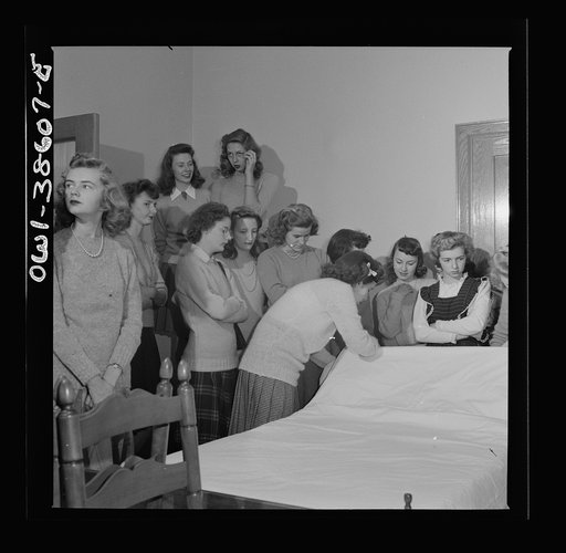 Washington, D.C. Home management students at Woodrow Wilson High School giving a demonstration in bedmaking. There is a model bedroom, living room, kitchen, and laundry for use by home economics students