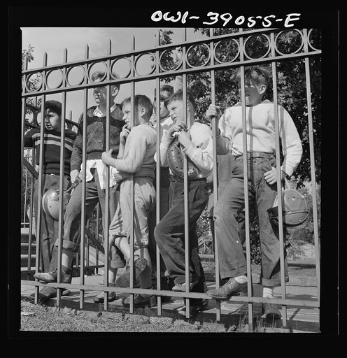 Washington, D.C. Young football fans, unable to finance a ticket to the Woodrow Wilson High School-Georgetown Preparatory School game, watch it through the fence at Woodrow Wilson High School