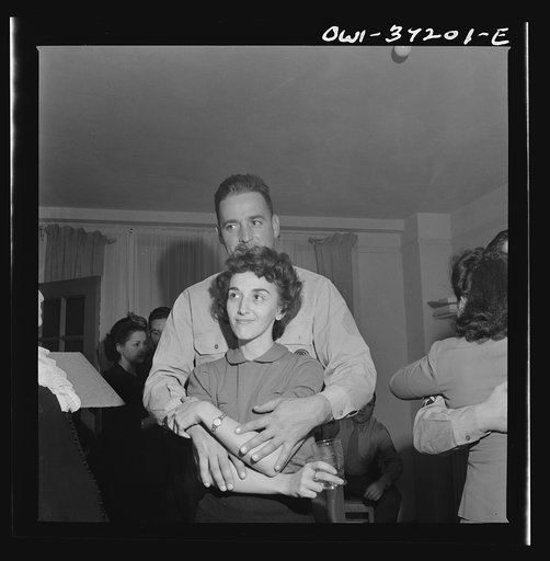 Untitled photo, possibly related to: Washington, D.C. Serviceman and a girl looking at pictures at a party