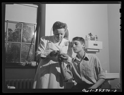 Washington, D.C. The school nurse removing a bandage from the finger of a student who was hurt while working in the wood shop at the Woodrow Wilson High School