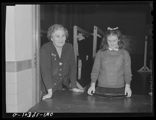 Washington, D.C. A custodial worker acts as checkroom attendent at the regimental ball at Woodrow Wilson High School. Her daughter is helping her