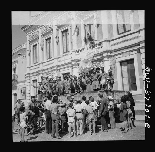 Sicilian prisoners of war, enroute to their homes, in the square of a small village exchanging greetings with the townfolk