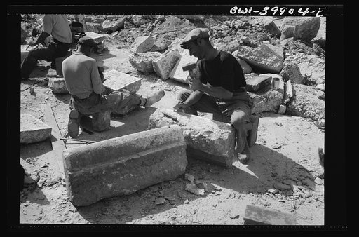 Sicilian workmen breaking stone to be used in repairing the roads demolished by the Germans in retreat