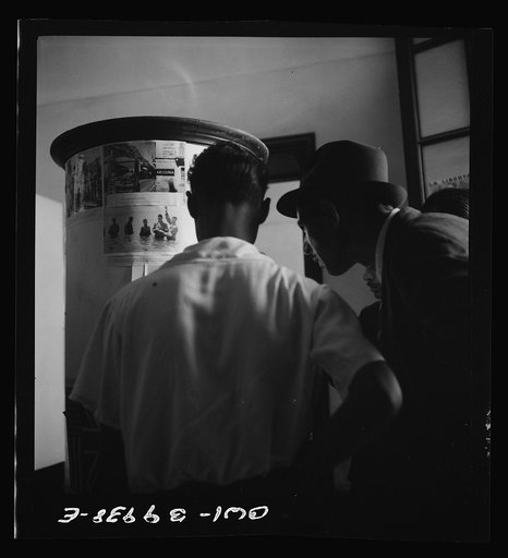 Catania, Sicily. Looking at photos and reading the news of life in Allied countries. This is of particular interest to Sicilians because it had been denied them during the Fascist years