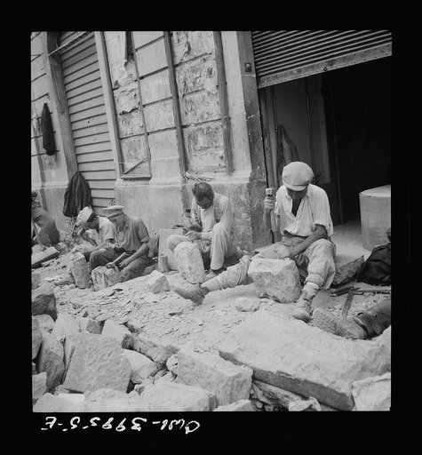 Sicilian workmen breaking stone to be used in repairing the roads demolished by the Germans in retreat