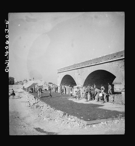 When the Germans fled Sicily they dynamited every bridge and road juction they had time to. But Allied army engineers and Sicilian workers are repairing the arteries so that normal traffic may flow once again over the island