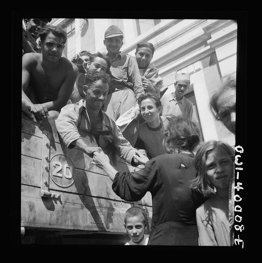 Fond relatives throng the Sicilian town square to greet their sons and sweethearts and uncles and nephews who were released from prison camps by the Allies