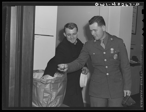 Washington, D.C. Sampling a basket of apples which was given to servicemen at the United Nations service center by the telephone company on Thanksgiving Day