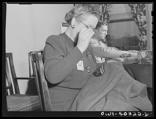Untitled photo, possibly related to: Washington, D.C. A volunteer at the United Nations service center sewing insignia and newly-acquired chevrons on the overcoat of a paratrooper