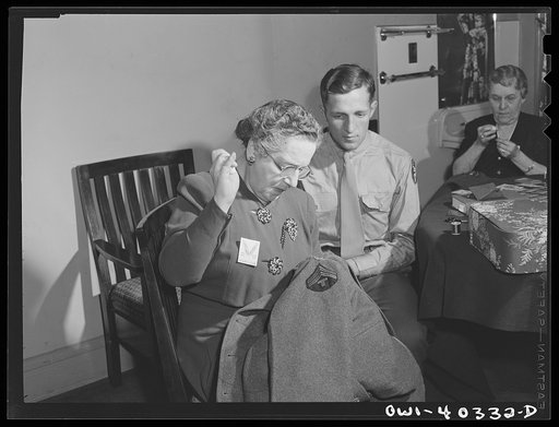 Washington, D.C. A volunteer at the United Nations service center sewing insignia and newly-acquired chevrons on the overcoat of a paratrooper