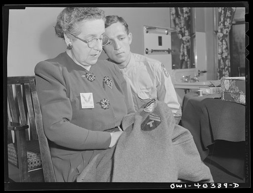 Washington, D.C. A volunteer at the United Nations service center sewing insignia and newly-acquired chevrons on the overcoat of a paratrooper