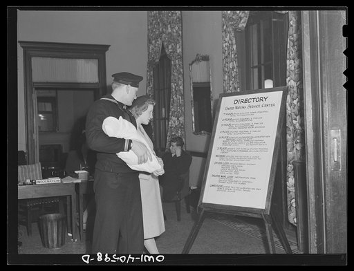 Washington, D.C. Hugh and Lynn Massman consulting the directory of the United Nations Service Center. Newly arrived in Washington, they find they can leave their baby in the nursery while they go sightseeing