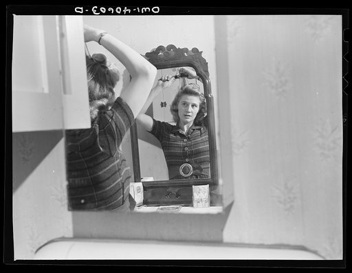 Washington, D.C. Lynn Massman, wife of a second class petty officer who is studying in Washington, experimenting with a new hairdo while her infant son has his afternoon nap