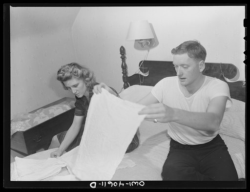 Washington, D.C. In the evening, Hugh Massman and his wife fold diapers. Joey's bureau drawer crib is moved to the side of their bed for the night