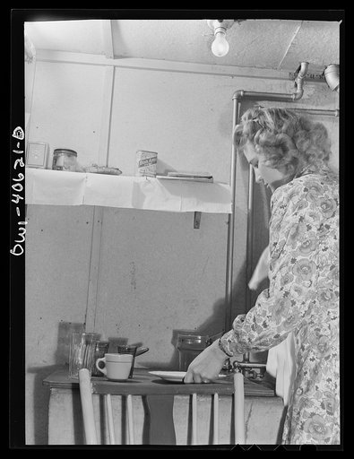 Washington, D.C. Lynn Massman, wife of a second class petty officer who is studying in Washington, does the breakfast dishes after feeding baby Joey