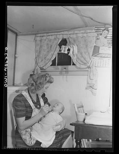 Washington, D.C. Lynn Massman, wife of a second class petty officer who is studying in Washington, D.C., feeding an eight weeks old son cereal