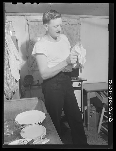 Washington, D.C. After dinner, Hugh Massman, a second class petty officer who is studying in Washington, does the dishes while Lynn feeds the baby