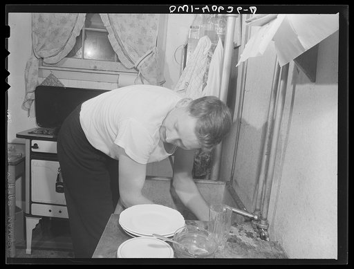 Washington, D.C. After dinner, Hugh Massman, a second class petty officer who is studying in Washington, does the dishes while Lynn feeds the baby
