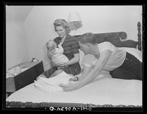 Washington, D.C. In the evening, Hugh Massman and his wife fold diapers. Joey's bureau drawer crib is moved to the side of their bed for the night