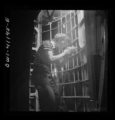 Boeing aircraft plant, Seattle, Washington. Production of B-17F (Flying Fortress) bombing planes. Girl working on the fuselage framework