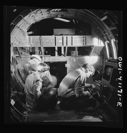 Untitled photo, possibly related to: Boeing aircraft plant, Seattle, Washington. Production of B-17 (Flying Fortress) bombing planes. A team of men and women workers complete assembly and fitting operations on the interior of a fuselage section
