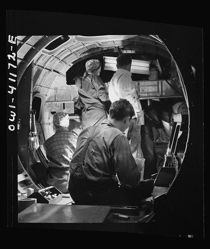 Boeing aircraft plant, Seattle, Washington. Production of B-17 (Flying Fortress) bombing planes. A team of men and women workers complete assembly and fitting operations on the interior of a fuselage section