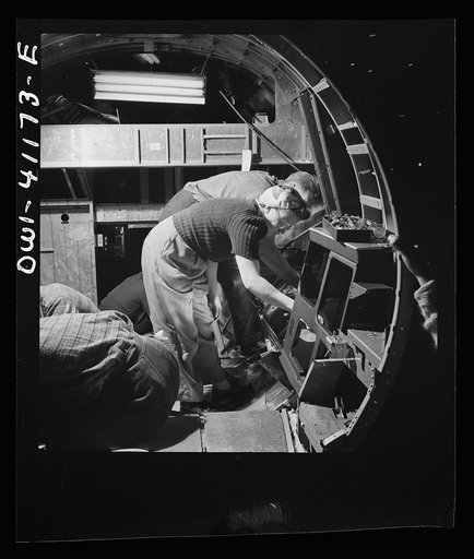 Boeing aircraft plant, Seattle, Washington. Production of B-17 (Flying Fortress) bombing planes. A team of men and women workers complete assembly and fitting operations on the interior of a fuselage section