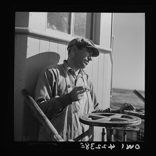 On board a fishing vessel out from Gloucester, Massachusetts. A winch man at the controls who has an important job as he controls the amount of trawl cable that is unwound from the winch. The amount of cable let out depends upon the depth of water, type of bottom, and tide conditions