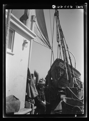 On board a fishing vessel out from Gloucester, Massachusetts. The power house, a riding sail, marker bouys, and canvas baskets