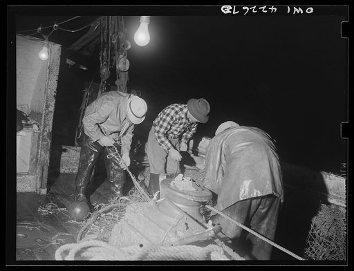 On board a fishing vessel out from Gloucester, Massachusetts. Repairing the trawl net during the night