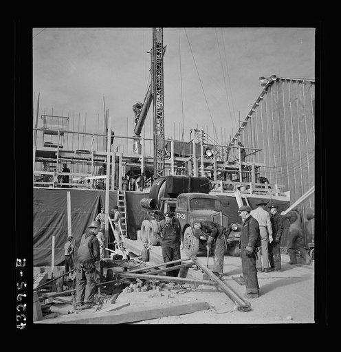Untitled photo, possibly related to: Columbia Steel Company at Geneva, Utah. Setting a pipe with a derrick during the construction of a new steel mill which will make important additions to the vast amount of steel needed for the war effort