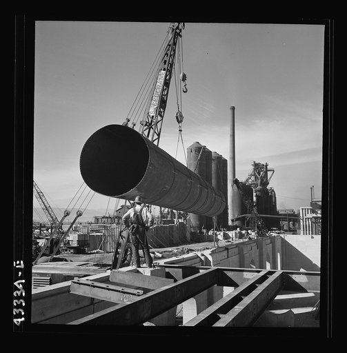 Untitled photo, possibly related to: Columbia Steel Company at Geneva, Utah. Setting a pipe with a derrick during the construction of a new steel mill which will make important additions to the vast amount of steel needed for the war effort