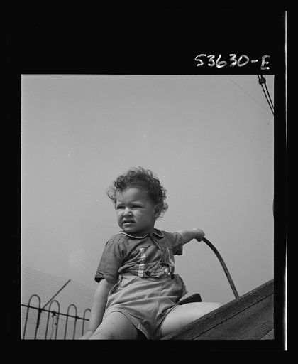 New York, New York. A small child whose mother works, enjoying outdoor play on the roof of Greenwich house which is well-equiped with swings, see-saws, and other things for those receiving day care