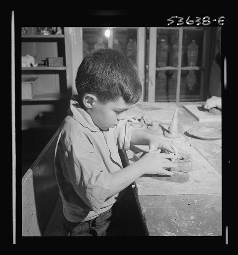New York, New York. A small boy enjoying his work in clay at Greenwich House where he receives day care while his mother works