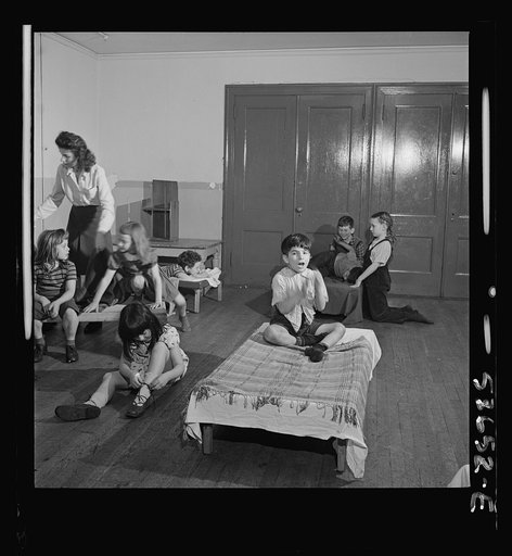 New York, New York. Children putting on their shoes after a rest period at Greenwich House where they receive day care while their mothers work