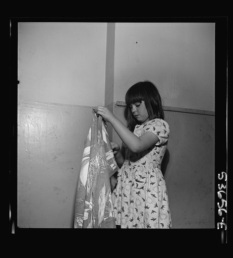 New York, New York. A little girl folding a blanket after a rest period at Greenwich House where she and many children receive day care while their mothers work. They enjoy work in clay, games, etc. as well as rest in this neighborhood center