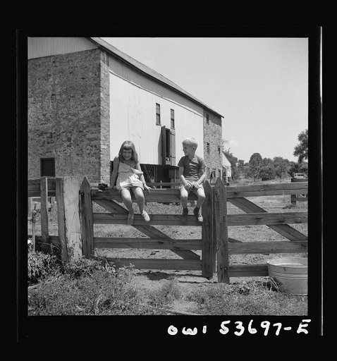 Dresher, Pennsylvania. Children sitting on a fence in front of a barn at the Spring Run Farm
