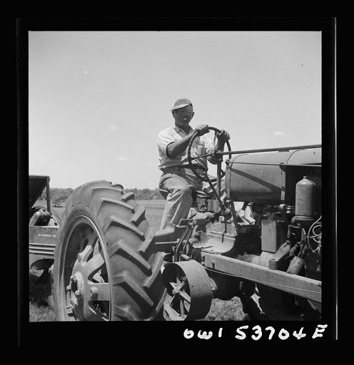 Dresher, Pennsylvania. The owner of a hay baler driving a tractor which hauls the baling machine at the Spring Run Farm