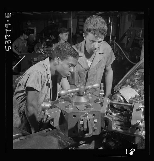 NYA (National Youth Administration) work center, Brooklyn, New York. Two turret-lathe workers, Negro and white, who are receiving training in machine shop practice, watching a cutting-off operation on a turret lathe