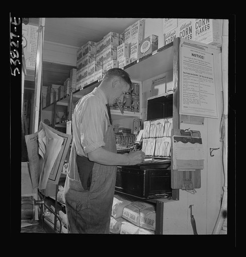 West Danville, Vermont. Mr. Hasings in his general store, figuring up, says, "You can't carry on a business, especially nowadays, without a lot of book work. But whether it is for income tax or making up price lists for cost of living comodities, it is all a part of keeping our government going so w