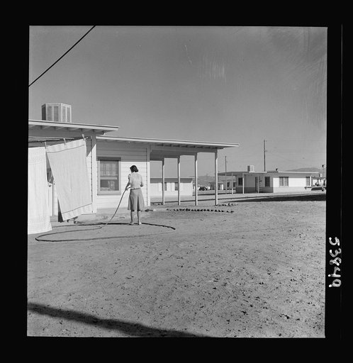 Las Vegas, Nevada. A worker's wife watering a newly planted lawn around one of the thousand demountable houses built adjacent to the Basic Magnesium Incorporated plant in the southern Nevada desert
