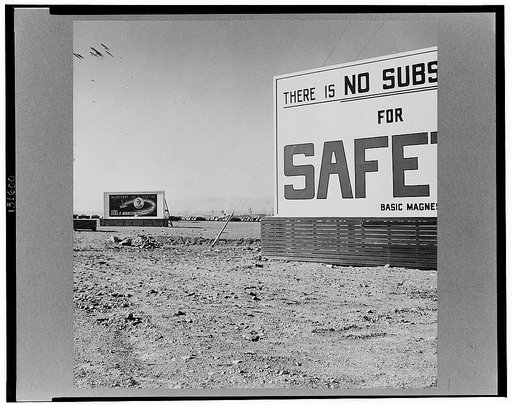 Las Vegas, Nevada. Billboards on the grounds of the gigantic plant of Basic Magnesium Incorporated, one of which shows tracer bullets and reads "MacArthur's job is fighting. OURS is magnesium"