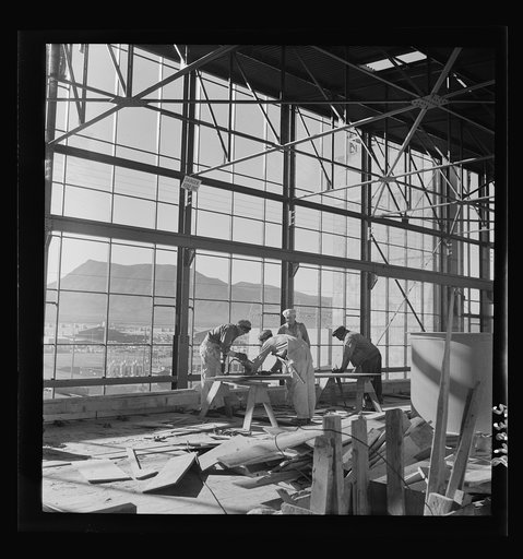 Las Vegas, Nevada. Workmen busy with woodwork inside the steel structure of one of the buildings of the Basic Magnesium Incorporated plant. Much of the plant can be seen in the background, and beyond it loom high mountains
