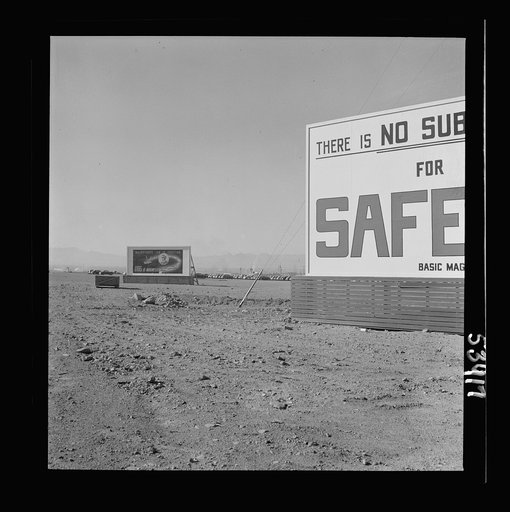 Untitled photo, possibly related to: Las Vegas, Nevada. Billboards on the grounds of the gigantic plant of Basic Magnesium Incorporated, one of which shows tracer bullets and reads "MacArthur's job is fighting. OURS is magnesium"