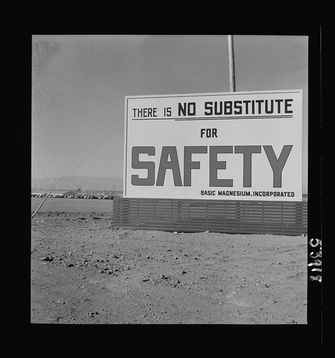 Untitled photo, possibly related to: Las Vegas, Nevada. Billboards on the grounds of the gigantic plant of Basic Magnesium Incorporated, one of which shows tracer bullets and reads "MacArthur's job is fighting. OURS is magnesium"