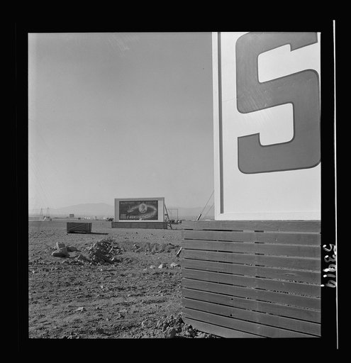 Untitled photo, possibly related to: Las Vegas, Nevada. Billboards on the grounds of the gigantic plant of Basic Magnesium Incorporated, one of which shows tracer bullets and reads "MacArthur's job is fighting. OURS is magnesium"