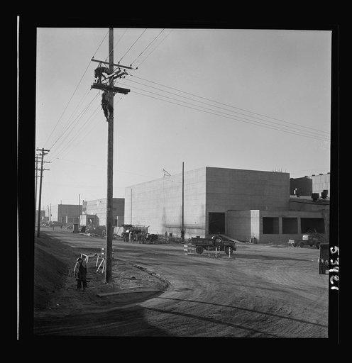 Untitled photo, possibly related to: Las Vegas, Nevada. A view of the plant of Basic Magnesium Incorporated, showing unfinished roads, power lines, telephone lines on which two men are working, and buildings during an early stage of construction