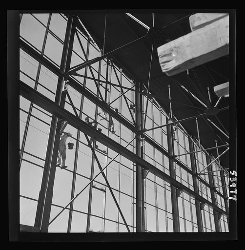 Untitled photo, possibly related to: Las Vegas, Nevada. Painters at work seventy feet above ground on the gigantic construction of the Basic Magnesium Incorporated plant in the southern Nevada desert. A tower of another building and mountain tops can be seen in the background
