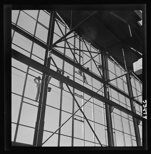 Untitled photo, possibly related to: Las Vegas, Nevada. Painters at work seventy feet above ground on the gigantic construction of the Basic Magnesium Incorporated plant in the southern Nevada desert. A tower of another building and mountain tops can be seen in the background