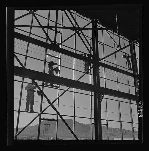 Untitled photo, possibly related to: Las Vegas, Nevada. Painters at work seventy feet above ground on the gigantic construction of the Basic Magnesium Incorporated plant in the southern Nevada desert. A tower of another building and mountain tops can be seen in the background